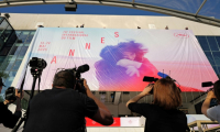 Des employés installent l'affiche officielle du 78e Festival de Cannes sur la façade du Palais des Festivals à Cannes, dans le sud-est de la France, le 11 mai 2025 ( AFP / Valery HACHE )