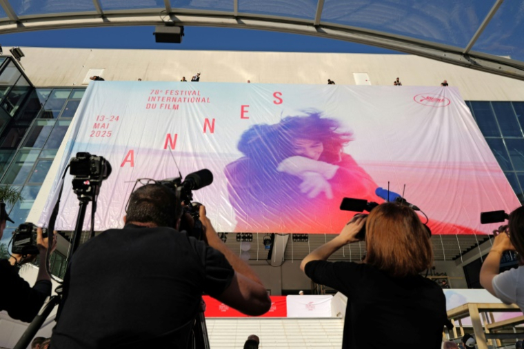 Des employés installent l'affiche officielle du 78e Festival de Cannes sur la façade du Palais des Festivals à Cannes, dans le sud-est de la France, le 11 mai 2025 ( AFP / Valery HACHE )