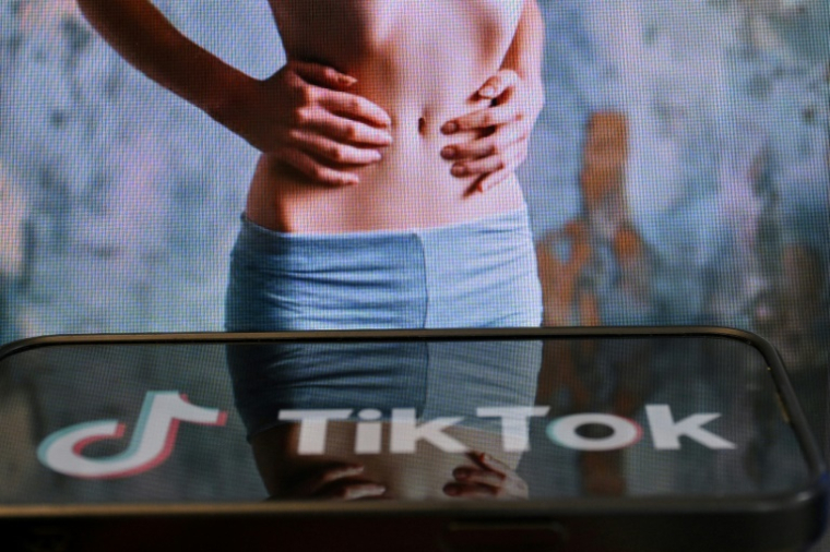 Photo d'illustration du 7 mai 2025 montrant le logo de Tik Tok sur un smartphone devant un écran affichant l'image d'une femme très mince, alors que la tendance "skinnytok" promouvant la minceur inquiète les experts ( AFP / Nicolas TUCAT )