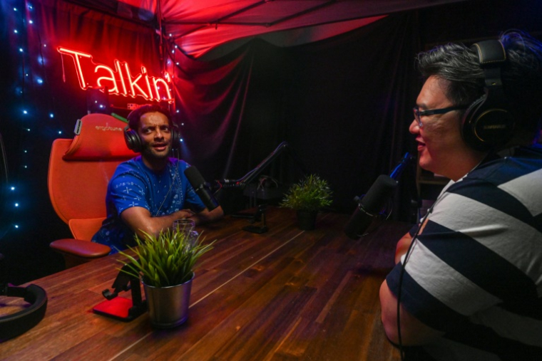Les animateurs de "Yah Lah Bu", Terence Chia (d) et Haresh Tilani (g), enregistrent un épisode dans leur studio de podcast à Singapour, le 10 avril 2025 ( AFP / Roslan RAHMAN )