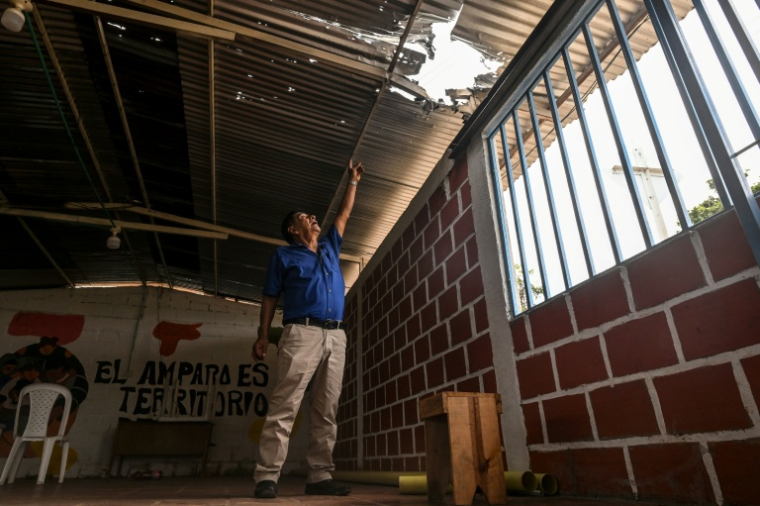 Le dirigeant communautaire colombien José Moran montre un trou dans un toit provoqué par une explosion à Suarez, dans le département du Cauca, en Colombie, le 27 mai 2026 ( AFP / Joaquín SARMIENTO )