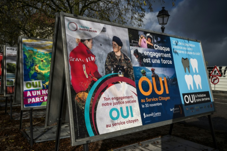 Des affiches électorales en faveur d'une initiative instaurant le devoir civique obligatoire pour tous dans une rue à Genève, le 25 novembre 2025 en Suisse ( AFP / Fabrice COFFRINI )