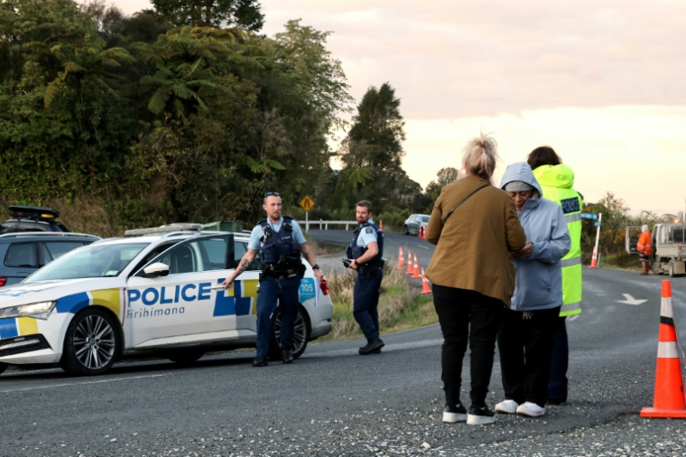 La police et des habitants près de l'endroit où un homme en cavale depuis près de quatre ans avec ses trois enfants a été abattu dans le nord de la Nouvelle-Zélande, le 8 septembre 2025 ( AFP / DJ MILLS )