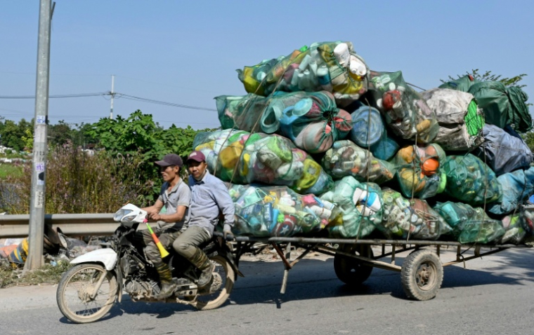 Deux hommes tractent à moto des déchets en plastique destinés à être recyclés aux alentours de Hanoï, au Vietnam, le 25 novembre 2025 ( AFP / Nhac NGUYEN )