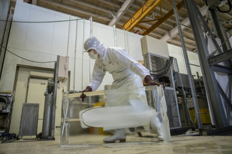 Un employé déplace de la glace à l'usine Kuramoto Ice à Kanazawa, au Japon, le 15 juin 2026 ( AFP / Yuichi YAMAZAKI )
