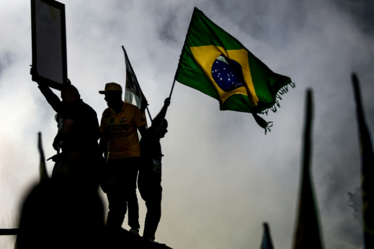 Un partisan du sénateur brésilien de droite et candidat à la présidence, Flavio Bolsonaro, agite un drapeau national lors d'un meeting de campagne à  Rio de Janeiro, le 3 octobre 2026 ( AFP / Douglas SHINEIDR )