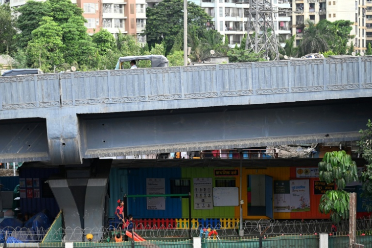 Des élèves jouent dans  "l'école du feu rouge", qui accueille des enfants défavorisés dans des conteneurs aménagés en salles de cours sous un pont autoroutier, le 20 mai 2026 à Bombay ( AFP / Punit PARANJPE )