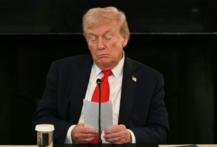 Le président américain Donald Trump lit une note remise par son secrétaire d'Etat Marco Rubio lors d'une réunion à la Maison Blanche, le 8 octobre 2025 à Washington ( AFP / Jim WATSON )