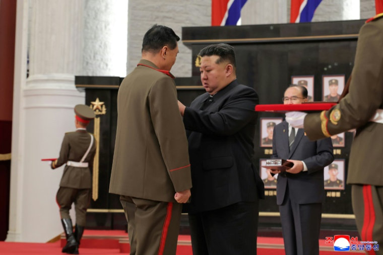 Photo non datée, publiée par l'agence de presse officielle nord-coréenne KCNA le 22 août 2025, du dirigeant nord-coréen Kim Jong-un (c) décorant un soldat lors d'une cérémonie au siège Parti des travailleurs de Corée à Pyongyang ( KCNA VIA KNS / STR )