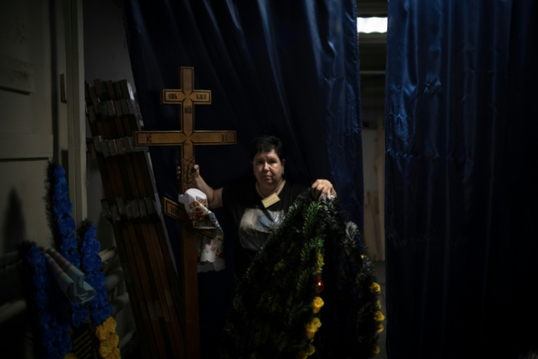 Svitlana Ostapenko, gérante du funérarium de Sumy, dans le nord-est de l'Ukraine, prépare, le 11 juin 2025, une croix et un couronne mortuaire pour l'enterrement d'un jeune soldat tué récemment lors de combats contre les forces russes ( AFP / Florent VERGNES )