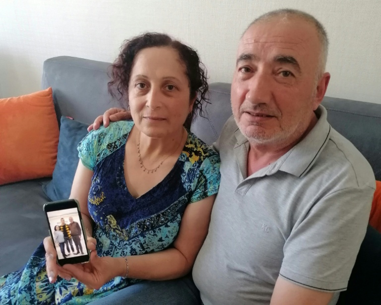 Kerban Kalin (g) et Ali Kalin (d) montrent une photo de leur fils, l'élève-officier Alper Kalin, qui purge une peine de prison à vie après la tentative de coup d'État de juillet 2016 en Turquie, chez eux à Ankara, le 12 juillet 2026 ( AFP / Anne CHAON )
