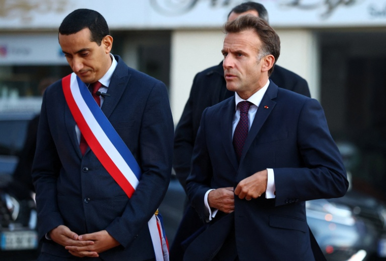 Le président français Emmanuel Macron (D) marche aux côtés du maire de Trappes, Ali Rabeh, à son arrivée pour une réunion à l'hôtel de ville après une fusillade survenue à Trappes, le 23 octobre 2026 ( POOL / Hannah McKay )