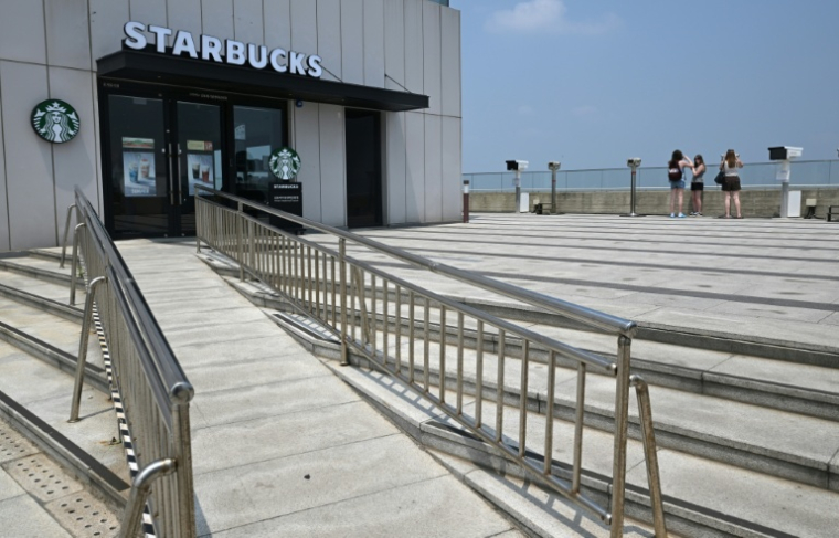 Des touristes observent la Corée du Nord depuis un point de vue à proximité d'un Starbucks située à l'Écoparc de la Paix d'Aegibong, à Gimpo, en Corée du Sud, le 1er juillet 2026  ( AFP / Jung Yeon-je )