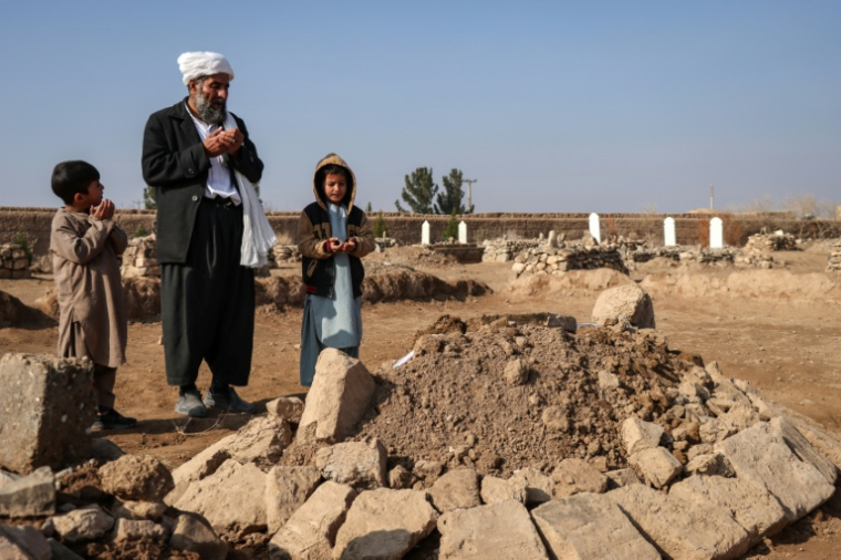 Gul Ahmad, au centre, et des proches prient sur la tombe de Habibullah dans le village de Ghunjan, en Afghanistan, le 26 décembre 2025 ( AFP / Mohsen KARIMI )