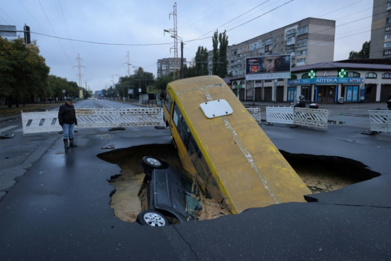Un bus et une voiture sont visibles dans un trou sur une route à Odessa, en Ukraine, après des pluies torrentielles ayant fait au moins 9 morts, le 1er octobre 2025 ( AFP / Oleksandr GIMANOV )