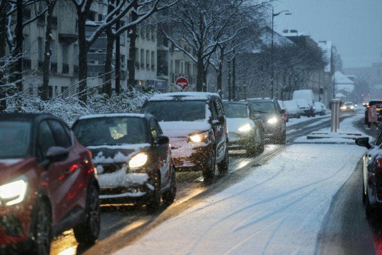 Des véhicules au ralenti dans Paris sous la neige, le 5 janvier 2026 ( AFP / Ludovic MARIN )