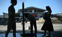 Des personnes se rafraîchissent à une fontaine publique près de la Grande Halle de La Villette alors qu'une vague de chaleur frappe le sud de l'Europe, à Paris, le 29 juin 2025 ( AFP / Julie SEBADELHA )