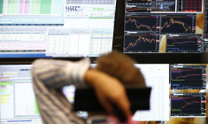 Un trader est assis devant les écrans d'ordinateur à son bureau à la bourse de Francfort