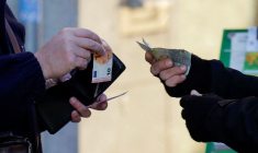 Un client échange un billet de dix euros contre deux billets de cinq euros auprès d'un vendeur de loterie de rue, à Ronda