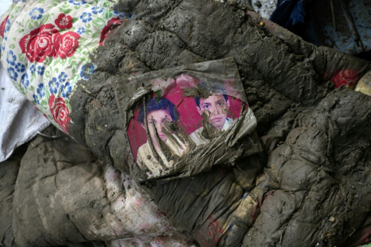 Une photo de famille souillée sur un matelas couvert de boue après la crue destructrice qui a fait plus de 600 morts à la frontière entre le Népal et la Chine, à Devighat, dans le district népalais de Nuwakot, le 29 août 2026 ( AFP / MANAN VATSYAYANA )