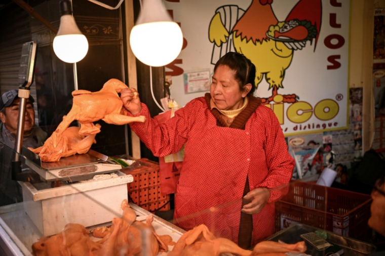 Une femme pèse un poulet pour le vendre dans un commerce du centre de La Paz, en Bolivie, le 22 juin 2026 ( AFP / MARTIN BERNETTI )