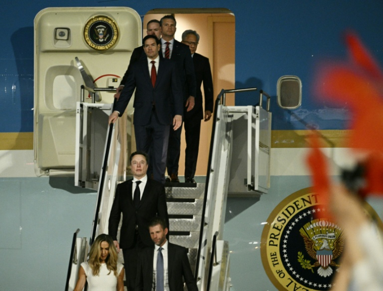 Eric et Lara Trump, Elon Musk (c), PDG de SpaceX, X et de Tesla, Marco Rubio, secrétaire d'État américain, Pete Hegseth, secrétaire à la Défense américain, et Jensen Huang, fondateur et PDG de Nvidia, descendent d'Air Force One à leur arrivée à l'aéroport international de Pékin, le 13 mai 2026 ( AFP / Brendan SMIALOWSKI )