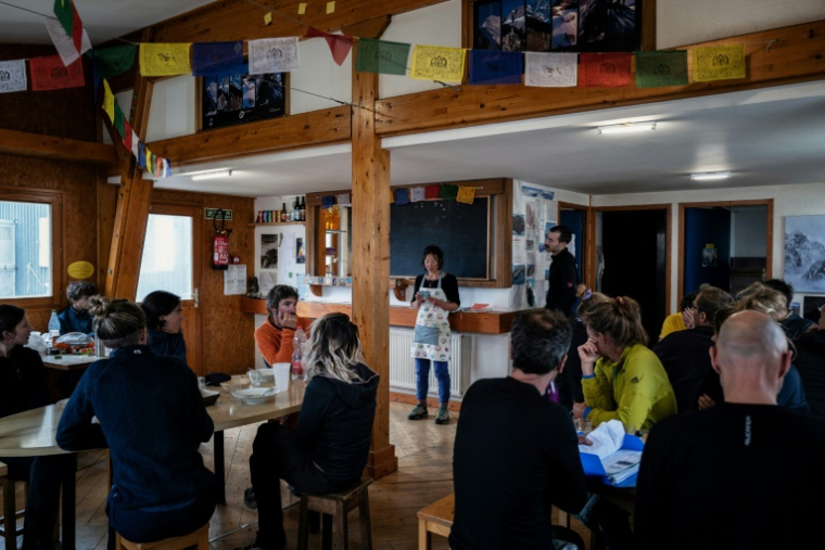 La gardienbe du refuge de la Selle annonce la météo des prochains jours aux alpinistes à la fin du dîner dans le massif des Écrins, à Saint-Christophe-en-Oisans, le 8 juillet 2025 ( AFP / JEFF PACHOUD )