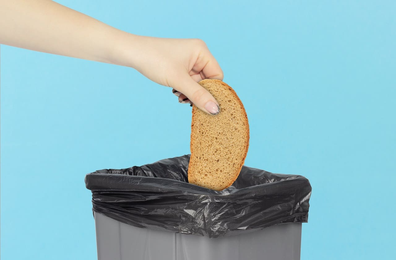 (Crédits photo : Adobe Stock - Gaspillage alimentaire avec un reste de pain jeté à la poubelle)