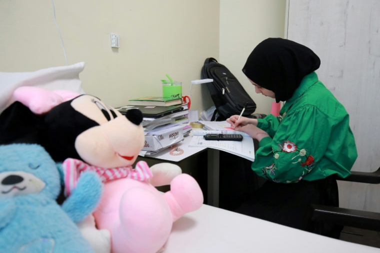 Chahd Tahrawi, blessée lors d'une frappe israélienne sur la bande de Gaza, étudie dans sa chambre de l'hôpital Al-Mouwasat, géré par Médecins sans frontières (MSF) à Amman, le 15 avril 2025 en Jordanie ( AFP / Khalil MAZRAAWI )