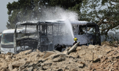 Un pompier israélien arrose une carcasse de bus après le tir d'un missile iranien à Herzliya, près de Tel-Aviv, le 17 juin 2025 ( AFP / Jack GUEZ )