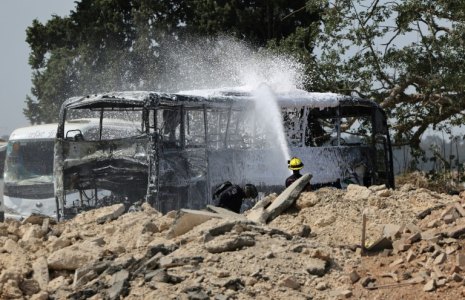 Un pompier israélien arrose une carcasse de bus après le tir d'un missile iranien à Herzliya, près de Tel-Aviv, le 17 juin 2025 ( AFP / Jack GUEZ )