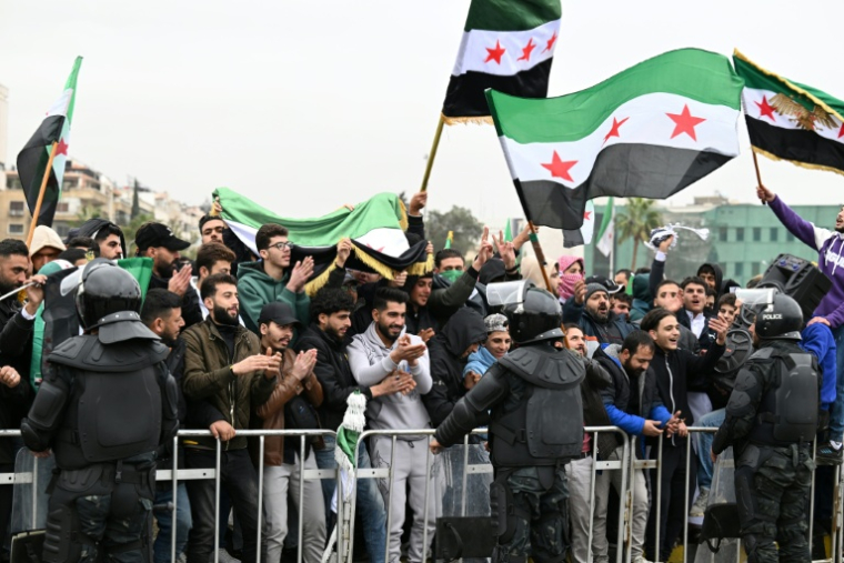 Des habitants brandissent des drapeaux syriens à Damas, pour célébrer le premier anniversaire de la destitution de Bachar al-Assad, le 8 décembre 2025 en Syrie ( AFP / LOUAI BESHARA )