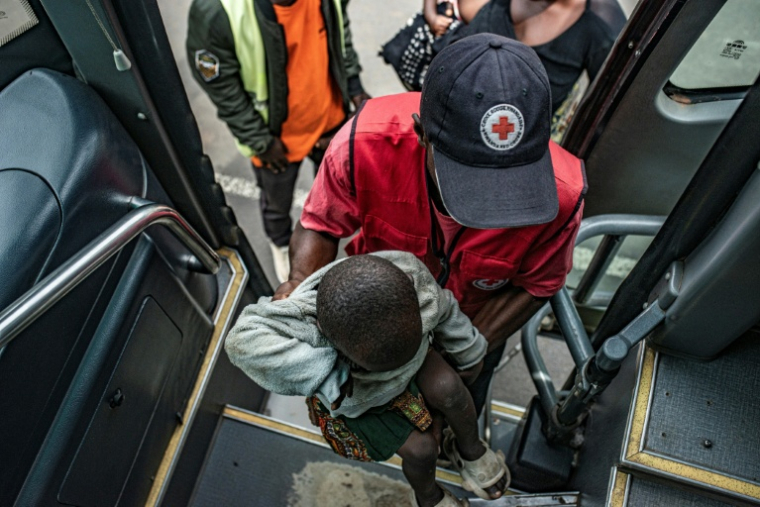 Un membre de la Croix-Rouge rwandaise aide un enfant qui a fui des combats en République démocratique du Congo à monter dans un bus à son arrivée à Bugarama, au Rwanda, le 5 décembre 2025 ( AFP / - )