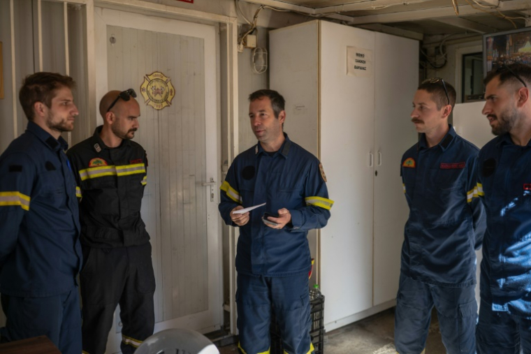 Apollos Kounis (c), chef d'un groupe local de pompiers volontaires, donne des instructions pour un dernier exercice de la saison avant de commencer le mois prochain les quarts de 24 heures au poste d'urgence, à Rodopoli, dans la banlieue d'Athènes, le 18 mai 2025 en Grèce ( AFP / Angelos TZORTZINIS )