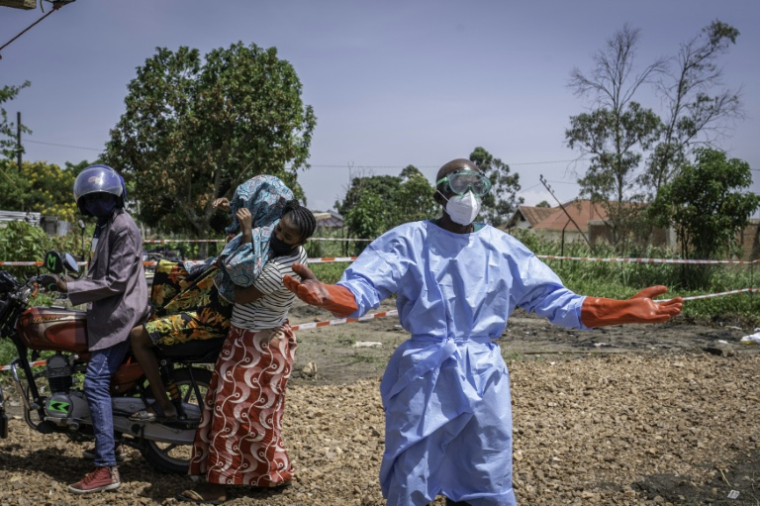 Dieudonné Sezabo, un agent de santé, demande de l'aide pour accueillir une jeune femme soupçonnée d'avoir la maladie Ebola, à l'hôpital de Rwampara, dans le nord-est de la République démocratique du Congo (RDC) le 26 mai 2026 ( AFP / Glody MURHABAZI )