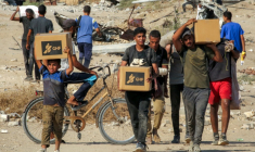 Des Palestiniens portent des cartons d'aide humanitaire reçus dans un centre de distribution géré par la Fondation humanitaire de Gaza (GHF), alors qu'ils traversent le "corridor de Netzarim", dans le centre de la bande de Gaza, le 22 août 2025 ( AFP / Eyad BABA )
