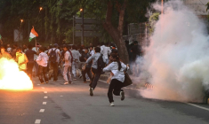 Des membres de la Rapid Action Force (RAF) tirent des grenades lacrymogènes pour disperser des partisans du "Parti du peuple des cafards" (CJP) lors d'une manifestation réclamant la démission du ministre de l'Éducation, en raison de fraudes présumées aux examens universitaires, le 20 juillet 2026 à New Delhi, en Inde ( AFP / Arun SANKAR )