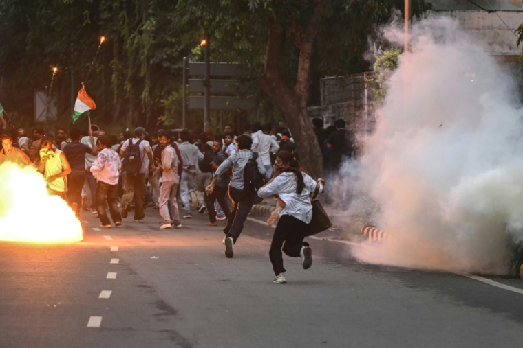 Des membres de la Rapid Action Force (RAF) tirent des grenades lacrymogènes pour disperser des partisans du "Parti du peuple des cafards" (CJP) lors d'une manifestation réclamant la démission du ministre de l'Éducation, en raison de fraudes présumées aux examens universitaires, le 20 juillet 2026 à New Delhi, en Inde ( AFP / Arun SANKAR )