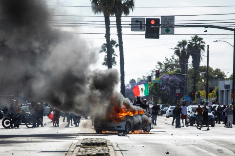 Une voiture en feu lors de manifestations contre les expulsions massives de sans-papiers, le 7 juin 2025 à Los Angeles ( AFP / RINGO CHIU )