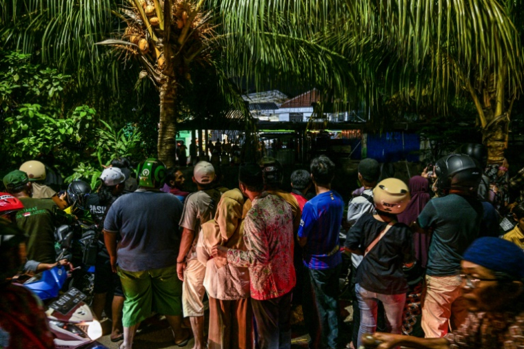 Des personnes regardent une opération de secours sur le site d'une école islamique mixte Al Khoziny qui s'est effondrée à 30 km de Surabaya, dans l'est de la grande île de Java, le 25 octobre 2025 ( AFP / Juni KRISWANTO )
