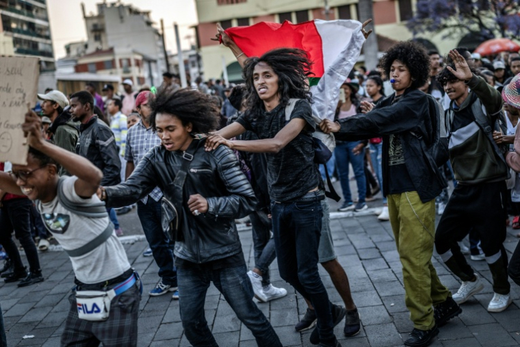 De jeunes habitants brandissent des drapeaux et dansent lors d'un concert de rock, célébrant la prise de pouvoir par l'armée à Antananarivo, le 14 octobre 2025 ( AFP / Luis TATO )