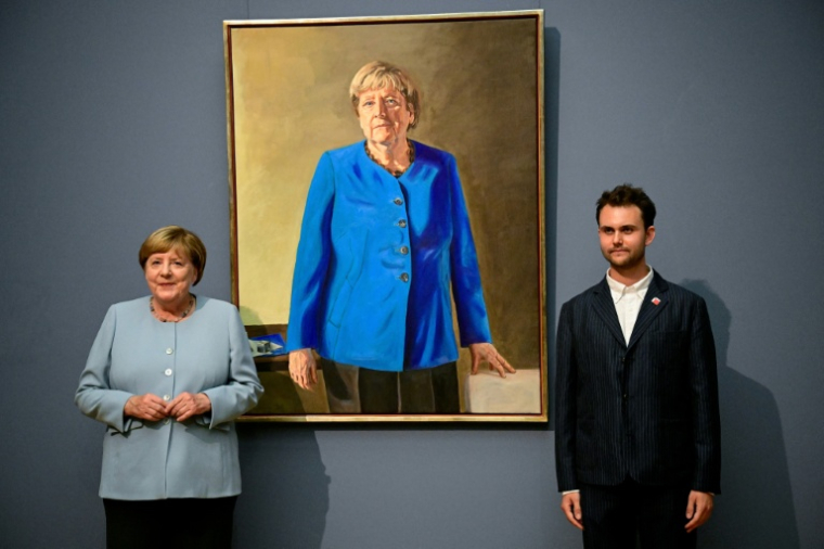 L’ancienne chancelière allemande Angela Merkel (à gauche) et l’artiste franco-allemand Jérémie Queyras (à droite) se tiennent à côté de sa peinture « Portrait de l’ancienne chancelière fédérale Angela Merkel » après son dévoilement au musée Bode à Berlin, le 30 juin 2026. ( AFP / Tobias SCHWARZ )