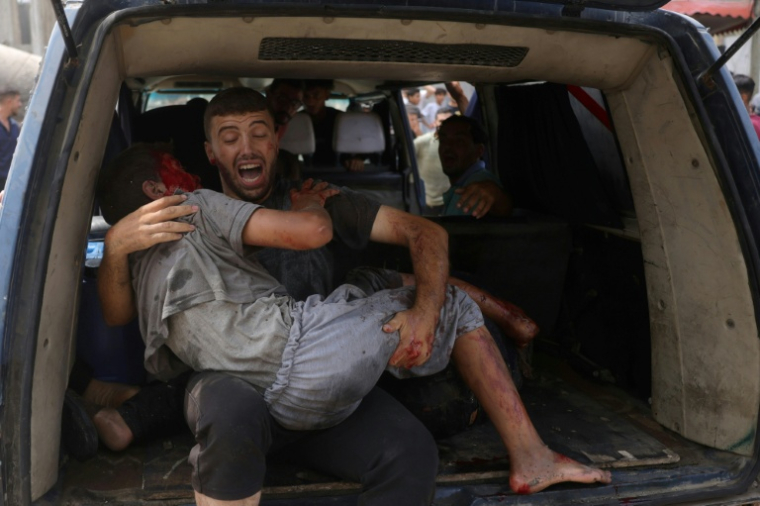 Un homme évacue un jeune blessé après une frappe israélienne à Gaza-ville, le 12 août 2025 ( AFP / BASHAR TALEB )