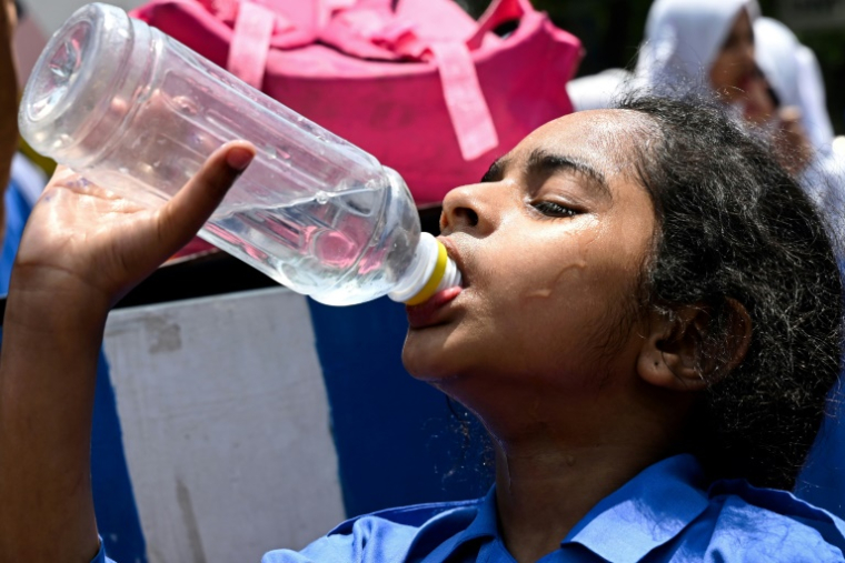 Une écolière boit de l'eau à Lahore, au Pakistan, par une journée particulièrement chaude le 26 mai 2025 ( AFP / Arif ALI )