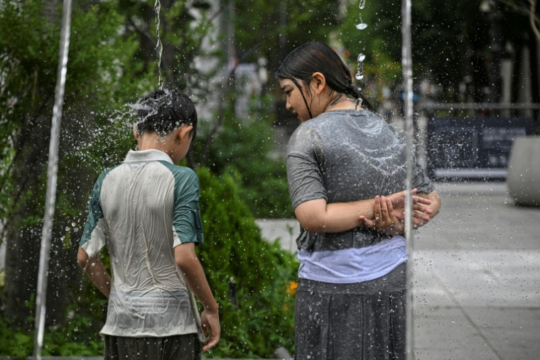 Des enfants se rafraîchissent sur des fontaines à jets, le 12 juillet 2026 à Séoul   ( AFP / JADE GAO )