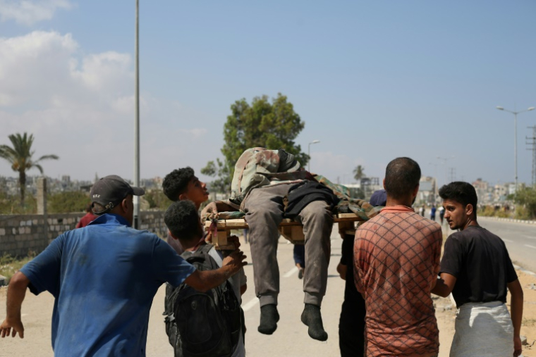 Des Palestiniens portent une personne tuée alors qu'elle venait chercher de l'aide dans un site de la Fondation humanitaire de Gaza (GHF), une organisation soutenue par Israël et les Etats-Unis, dans le centre de la bande de Gaza, le 2 août 2025 ( AFP / Eyad BABA )