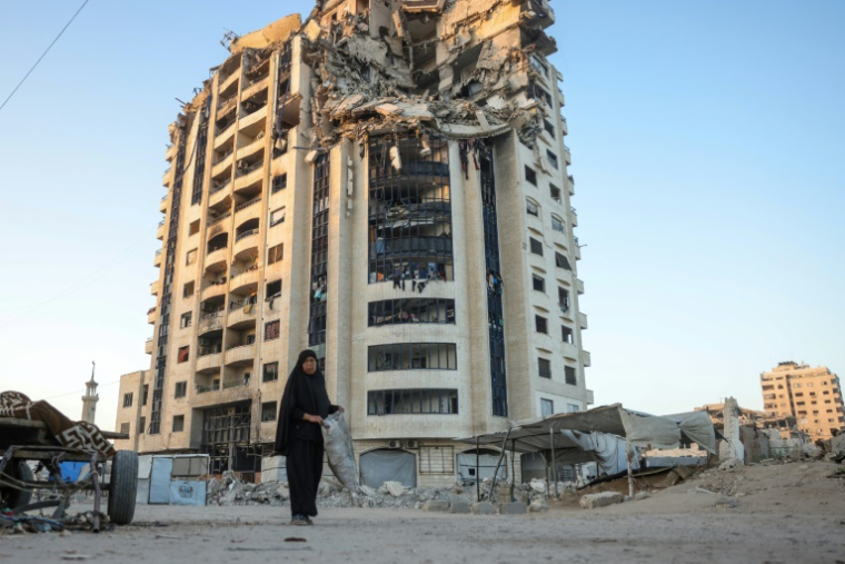 Une Palestinienne passe devant un bâtiment gravement endommagé dans la ville de Gaza, le 29 août 2025 ( AFP / BASHAR TALEB )