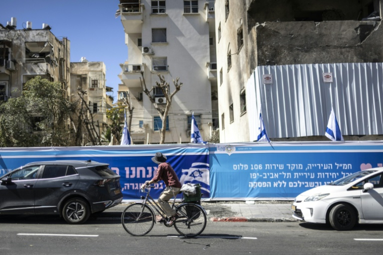 Un cycliste passe devant un immeuble endommagé par un missile iranien, le 8 mars 2026 à Tel-Aviv  ( AFP / OLYMPIA DE MAISMONT )