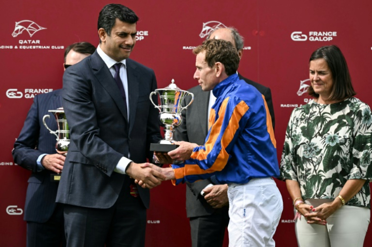 Le jockey britannique Ryan Moore (c) reçoit le trophée du 185e Prix du Jockey-Club, le 1er juin 2025 à Chantilly, dans l'Oise  ( AFP / Hugo MATHY )