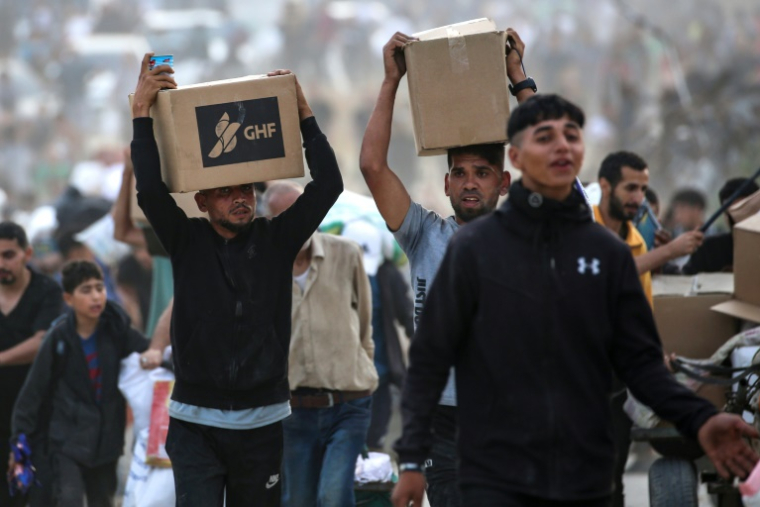 Des Palestiniens déplacés transportent des fournitures de secours distribuées par la Fondation humanitaire de Gaza (GHF), soutenue par les États-Unis, dans le centre de la bande de Gaza, le 8 juin 2025 ( AFP / Eyad BABA )